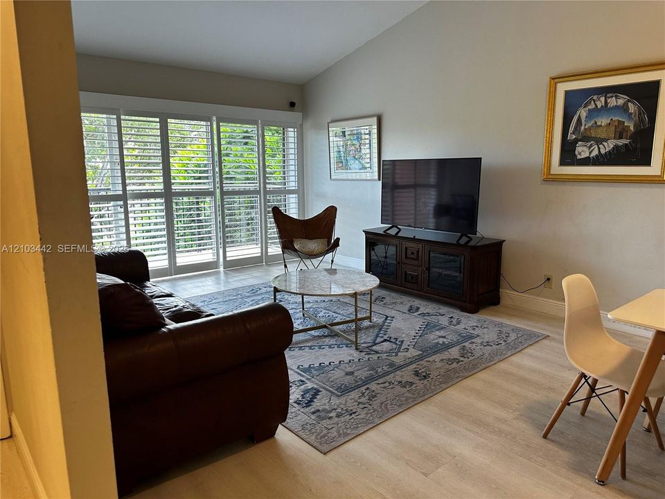 Vaulted ceilings, wood-finish flooring, and floor-to-ceiling sliding glass doors featuring custom plantation shutters