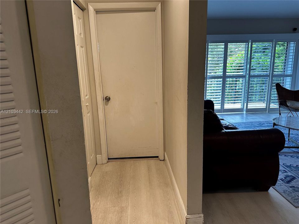 Wood-finish flooring, interior louvered bi-fold doors, and expansive floor-to-ceiling glass panel doors with interior shutters