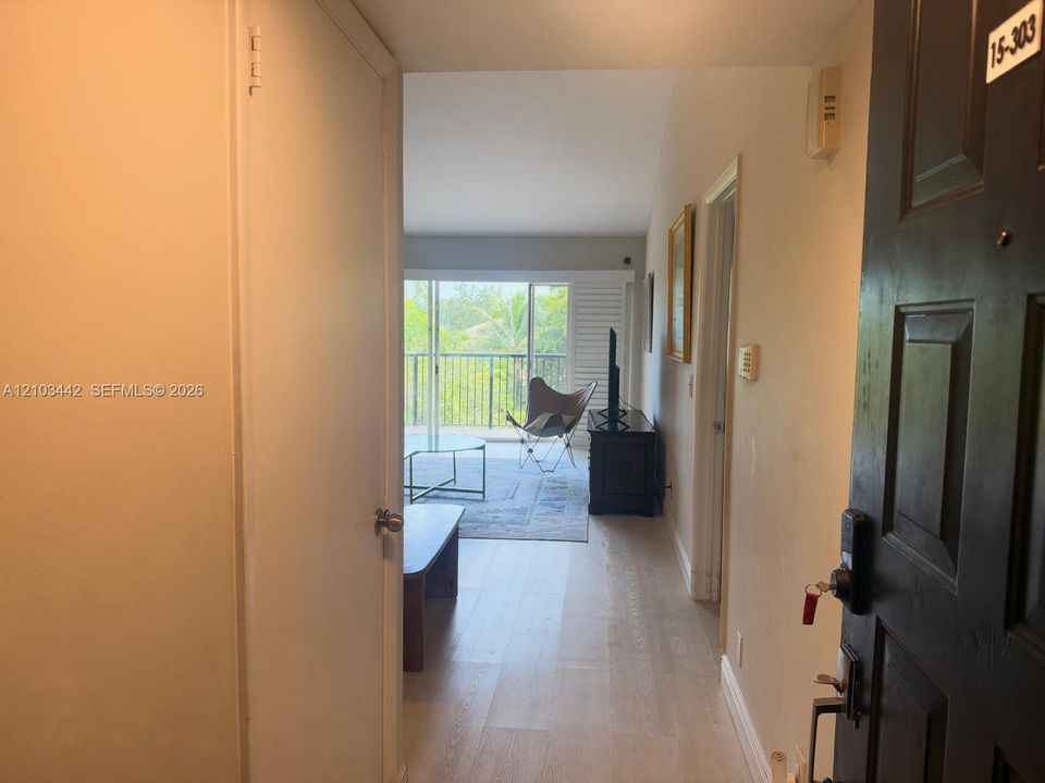 Entryway featuring wood-finish flooring, recessed door hardware, and an open layout with sliding glass doors leading to a balcony
