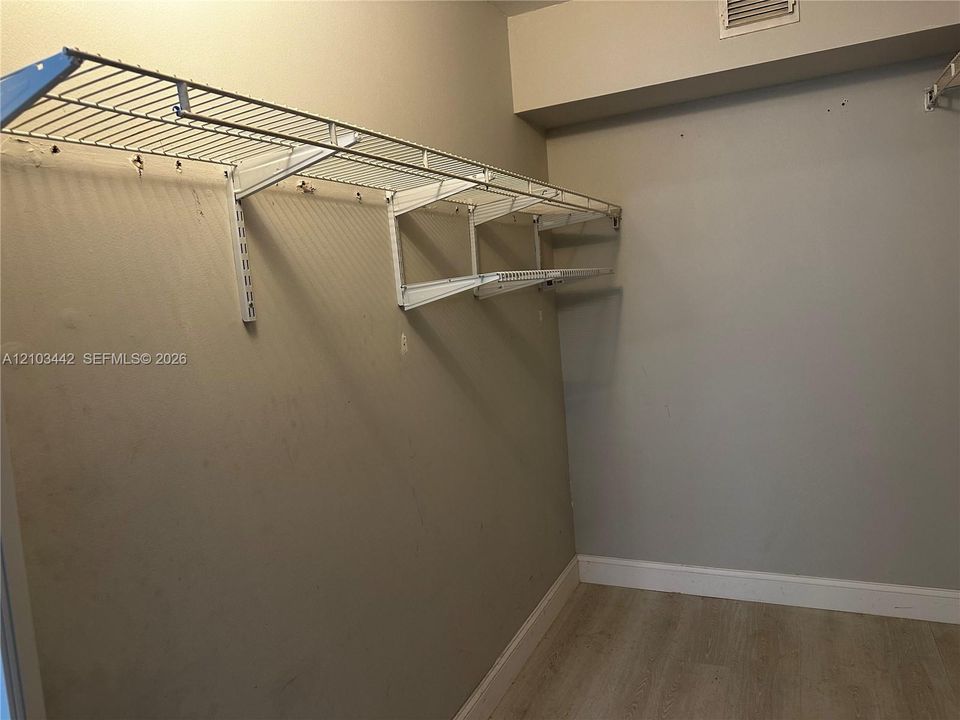 Storage space featuring neutral wall paint, wood-finish flooring, and white wire shelving