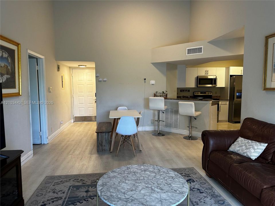 High ceilings, wood-finish flooring, and kitchen breakfast bar with overhead lighting
