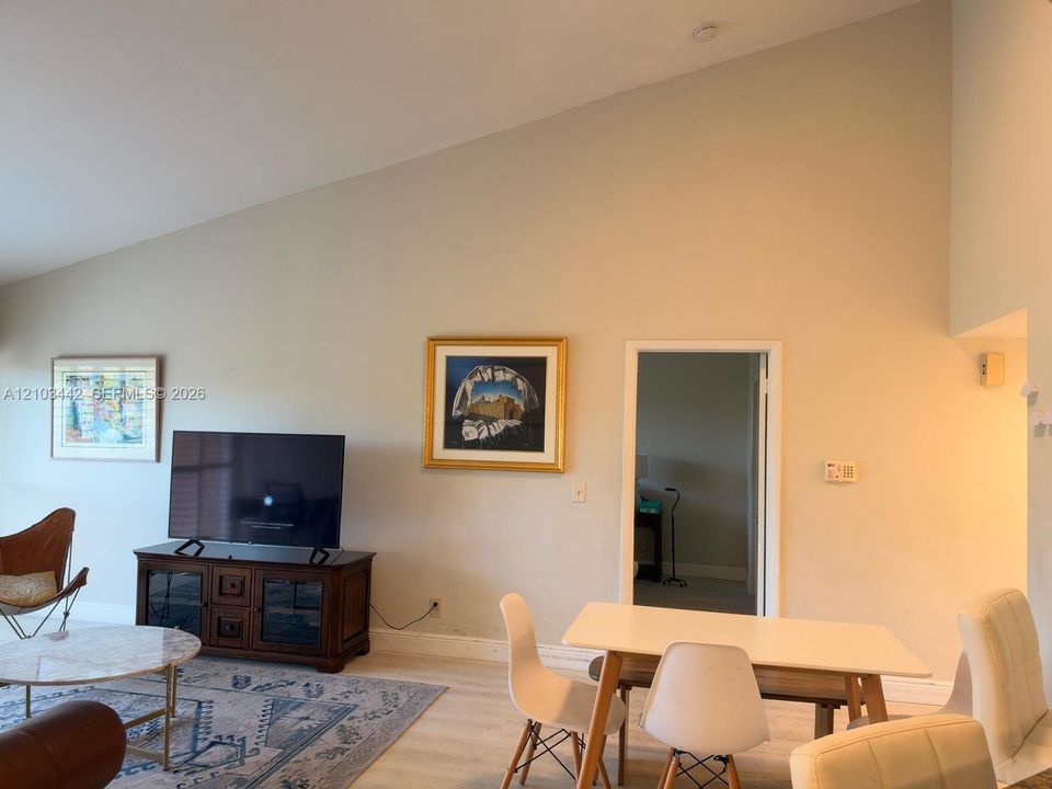 Vaulted ceiling featuring a neutral wall finish and wood-finish flooring