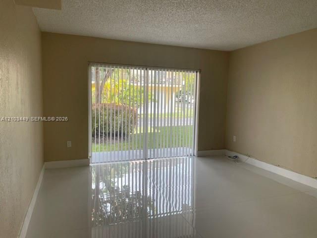 Interior space featuring large-format polished tile flooring, neutral wall tones, and sliding glass doors with vertical blinds