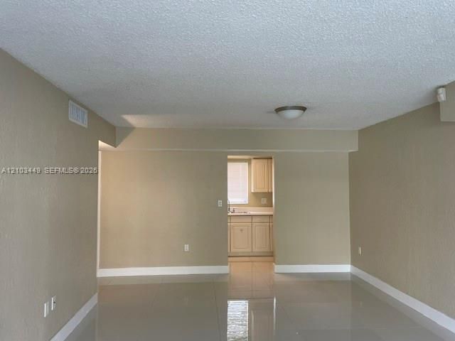 Interior space featuring neutral wall paint, polished tile flooring, and a flush-mount light fixture