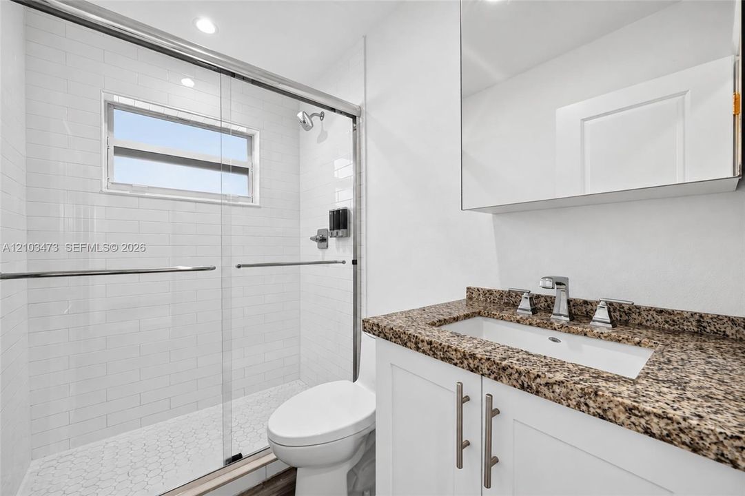 Shower with sliding glass doors, white subway tile surround, and a window