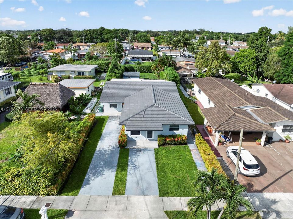 Contemporary style residence with a gray tile roof, featuring a concrete driveway with grass inserts, and perimeter landscaping