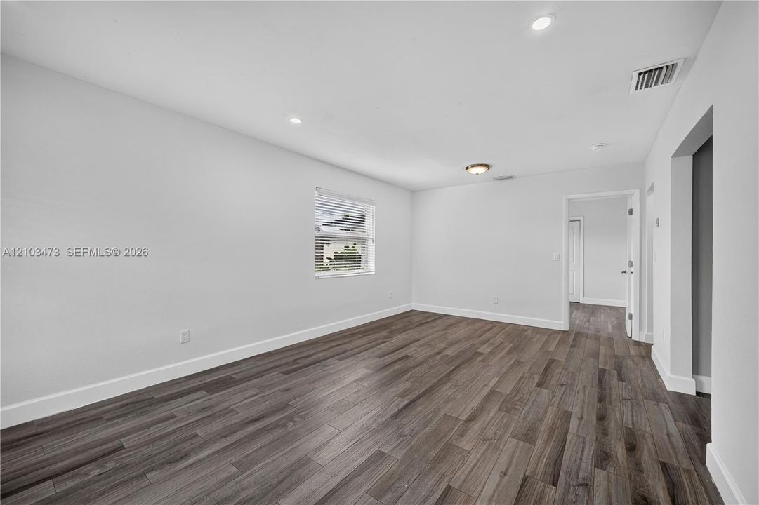Wood-finish flooring, recessed lighting, white walls, and a window with blinds