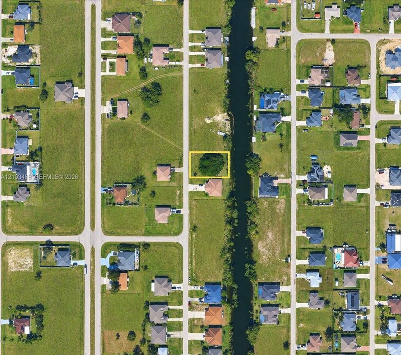 Vacant residential lot featuring direct canal access, established tree canopy, and road frontage