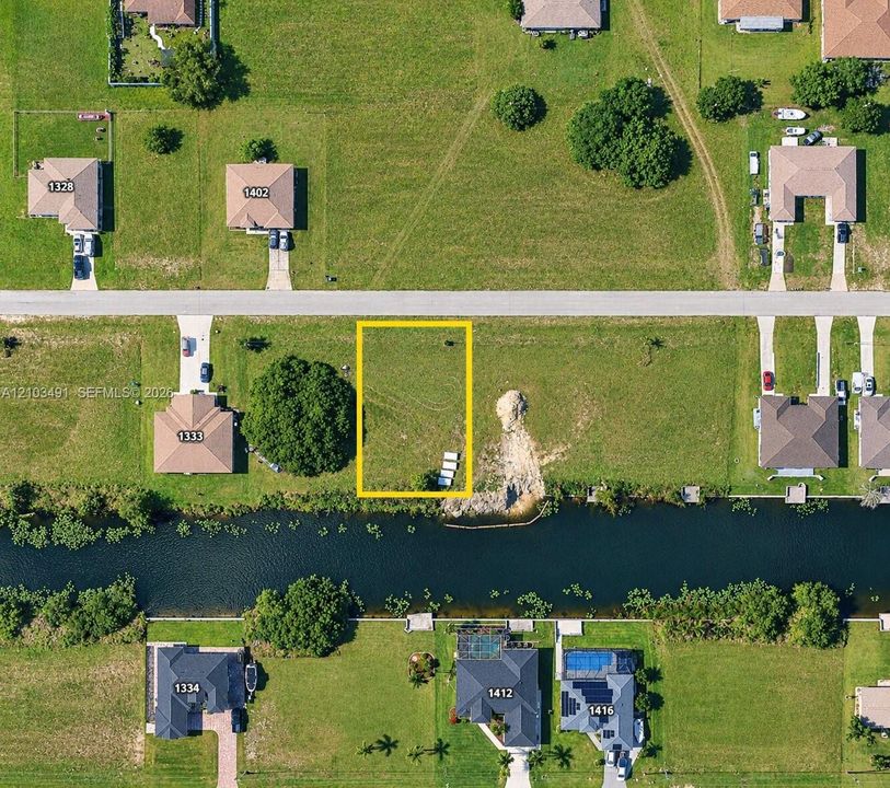 Vacant lot featuring direct canal access, established grass coverage, and rectangular parcel dimensions