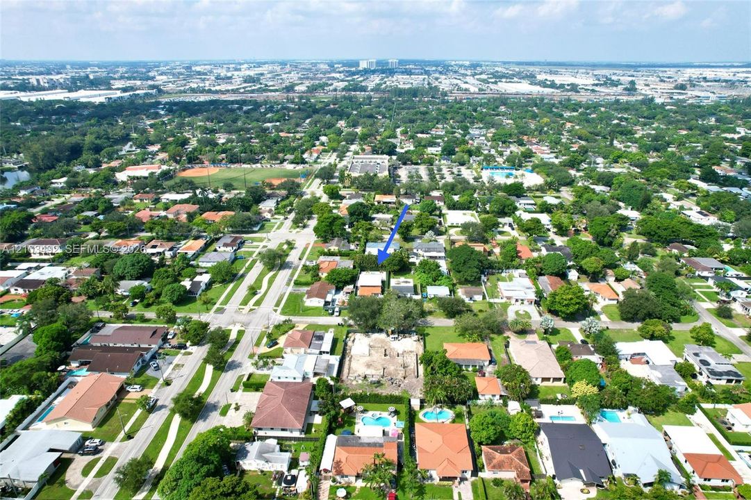 Aerial perspective of a residential lot featuring mature trees and established landscaping within a suburban setting