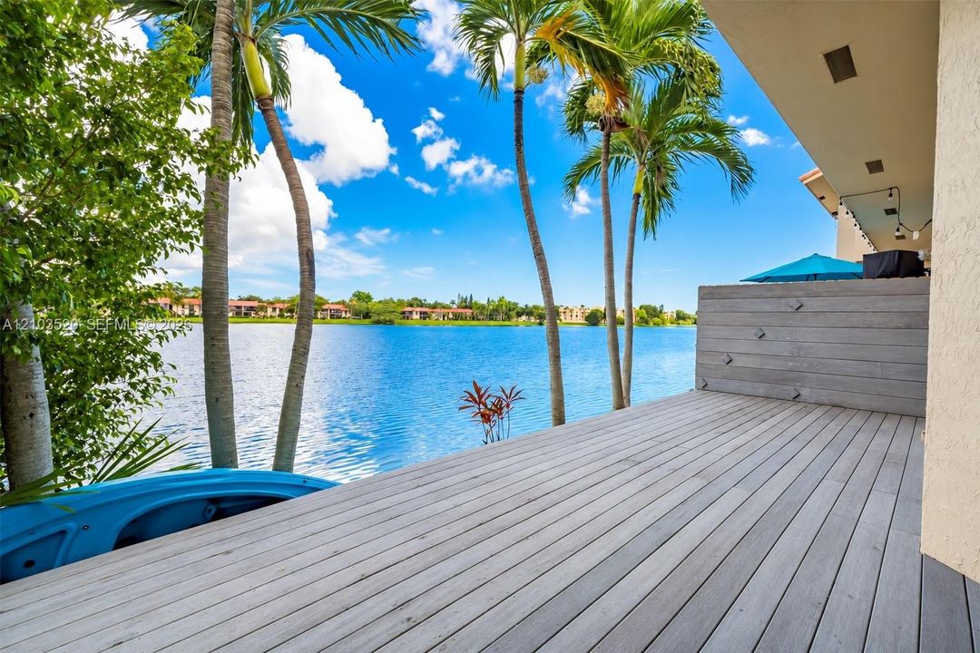 Waterfront wood-finish deck with a privacy screen, recessed lighting, and integrated palm trees