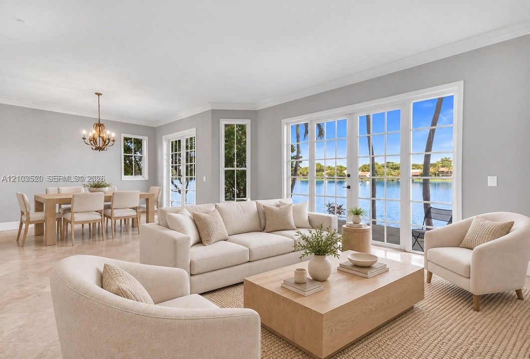 Open-concept living and dining area featuring stone-finish flooring, crown molding, multi-pane floor-to-ceiling glass doors, and a decorative chandelier