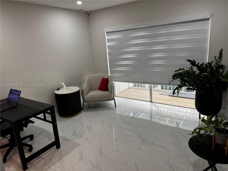 Large-format tile flooring with a neutral veined finish, floor-to-ceiling glass sliding doors, and adjustable dual-layer roller shades
