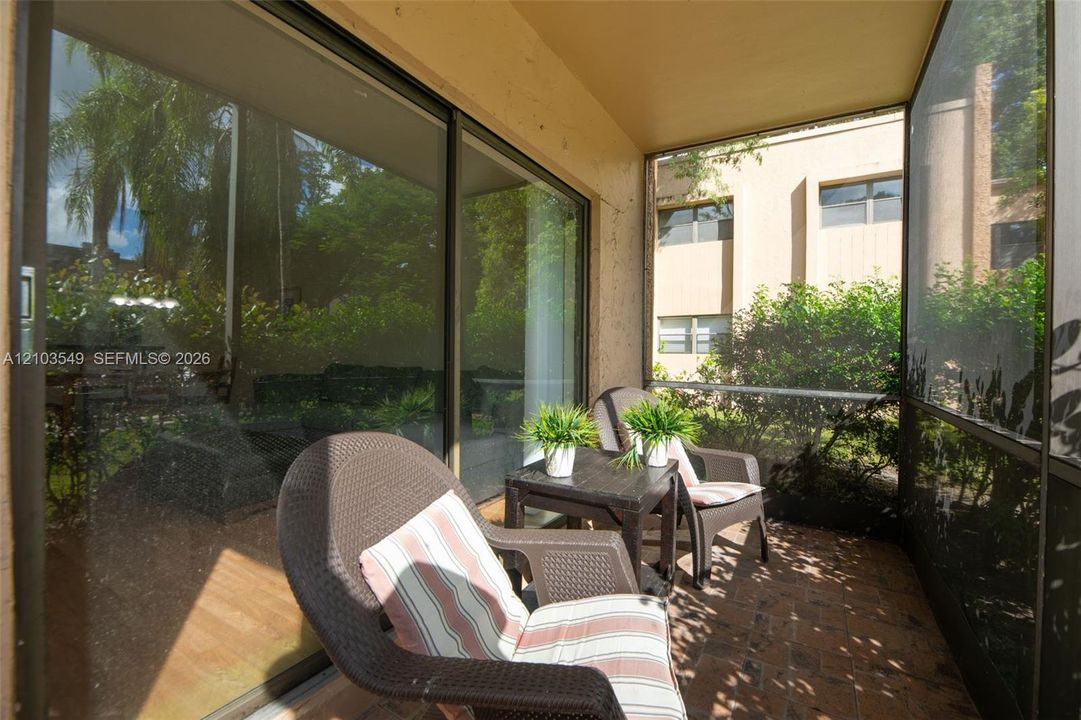Screened-in porch featuring brick paver flooring, sliding glass doors, and structured metal framing