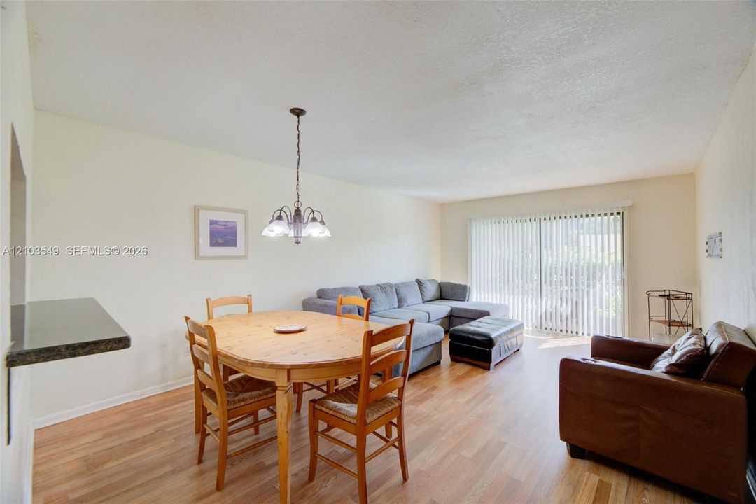 Wood-finish flooring, sliding glass doors, built-in breakfast bar, and multi-arm chandelier lighting