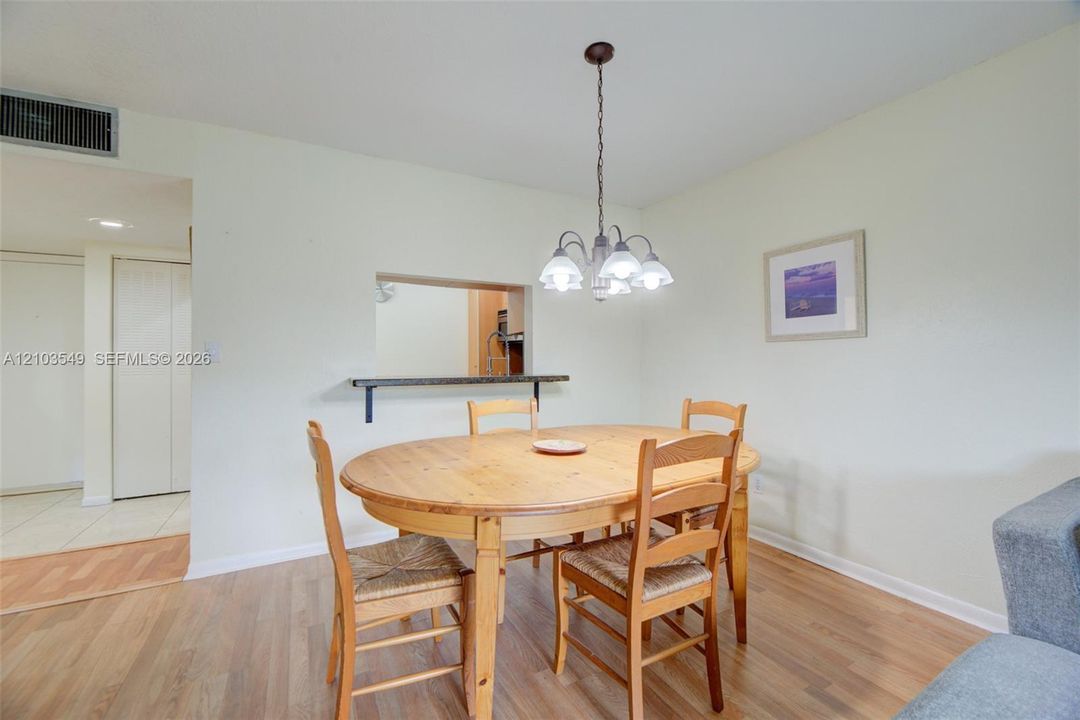Pass-through window with shelf, wood-finish flooring, and multi-light chandelier