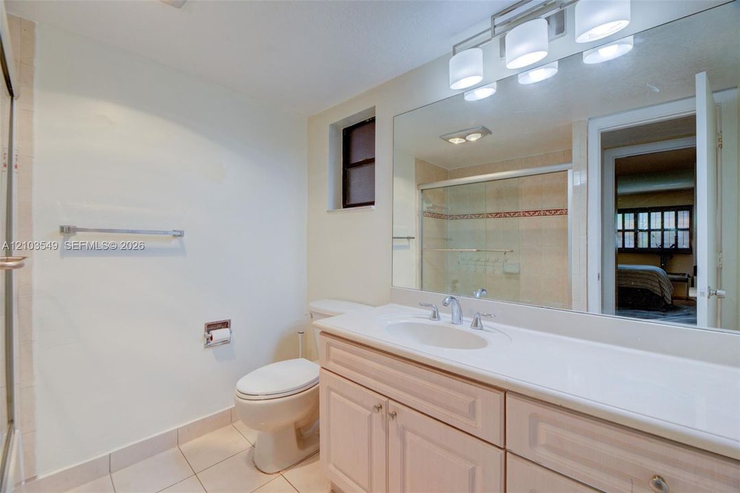 Bathroom featuring a vanity with integrated sink and countertop, full-width wall mirror, four-light vanity fixture, and a glass-enclosed shower