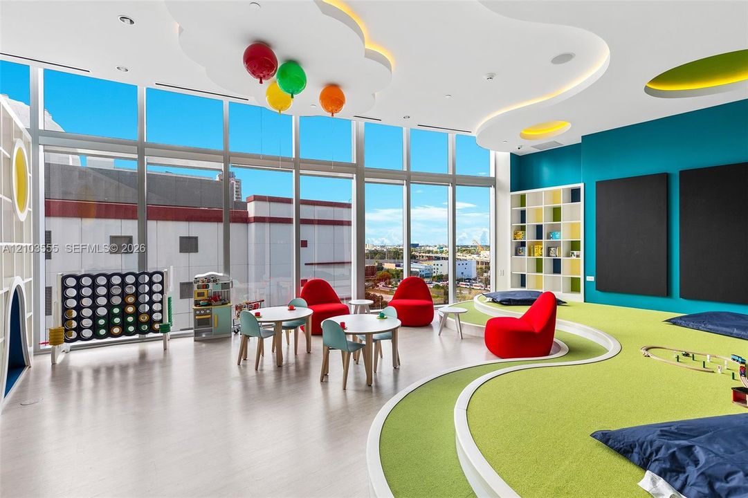 Expansive wall of windows, recessed lighting, built-in shelving, light wood-finish flooring, and a multi-level green carpeted area