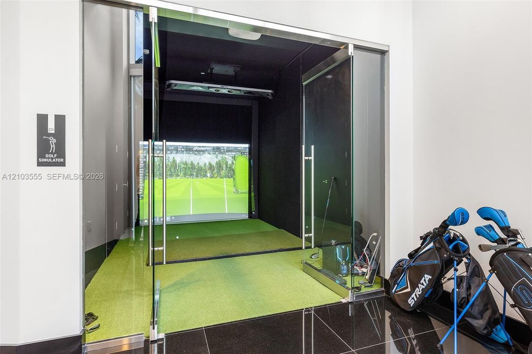 Dedicated golf simulator room featuring a large projection screen and artificial turf
