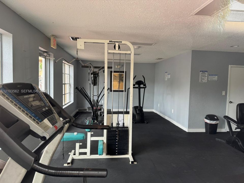 Fitness room featuring rubberized flooring, expansive windows, and recessed lighting