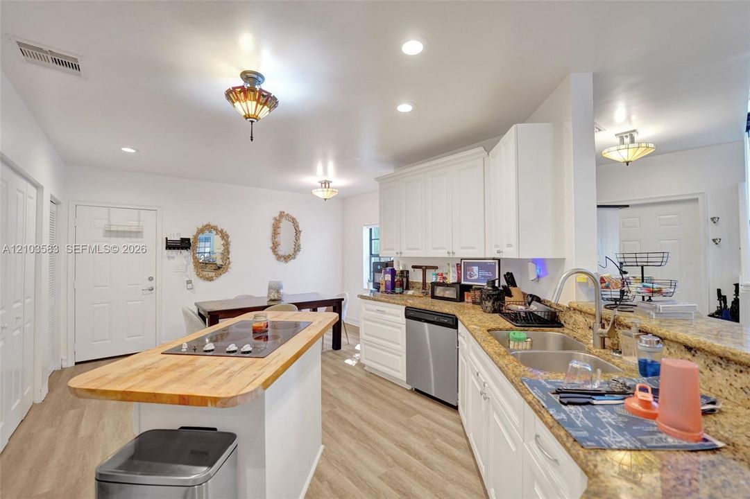 Kitchen featuring white cabinetry, stone-finish countertops, wood-finish flooring, central island with a wood-top surface, and stainless-steel appliances