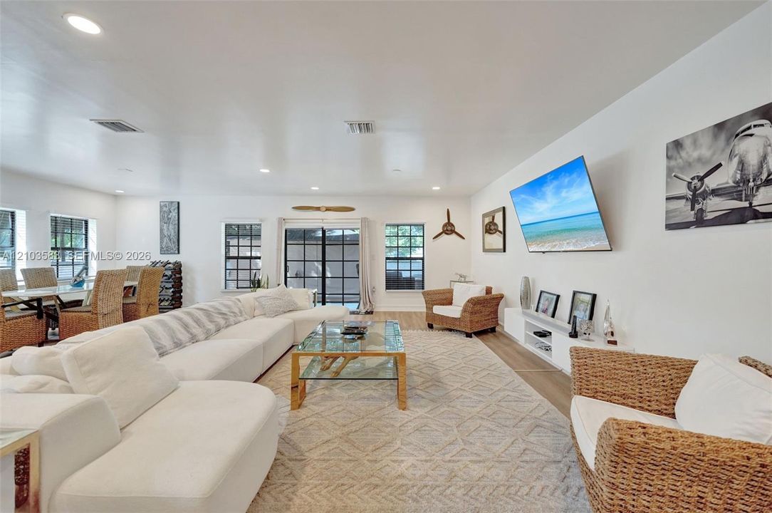 Open-concept living space featuring recessed lighting, wood-finish flooring, and sliding glass doors with grid-patterned frames