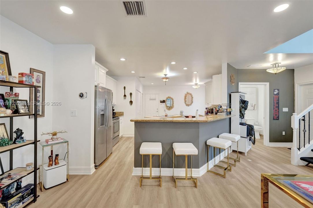 Kitchen featuring a breakfast bar with stone-surfaced countertops, stainless steel appliances, recessed ceiling lighting, and wood-finish flooring