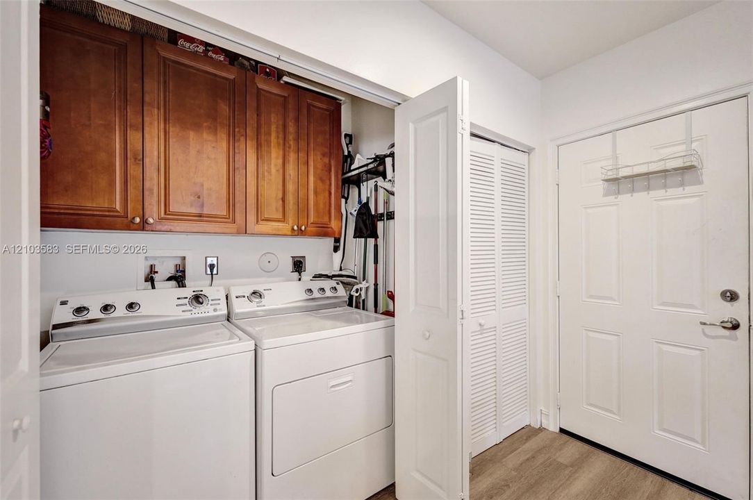 Laundry room featuring wood-finish cabinetry, louvered closet doors, and wood-finish flooring