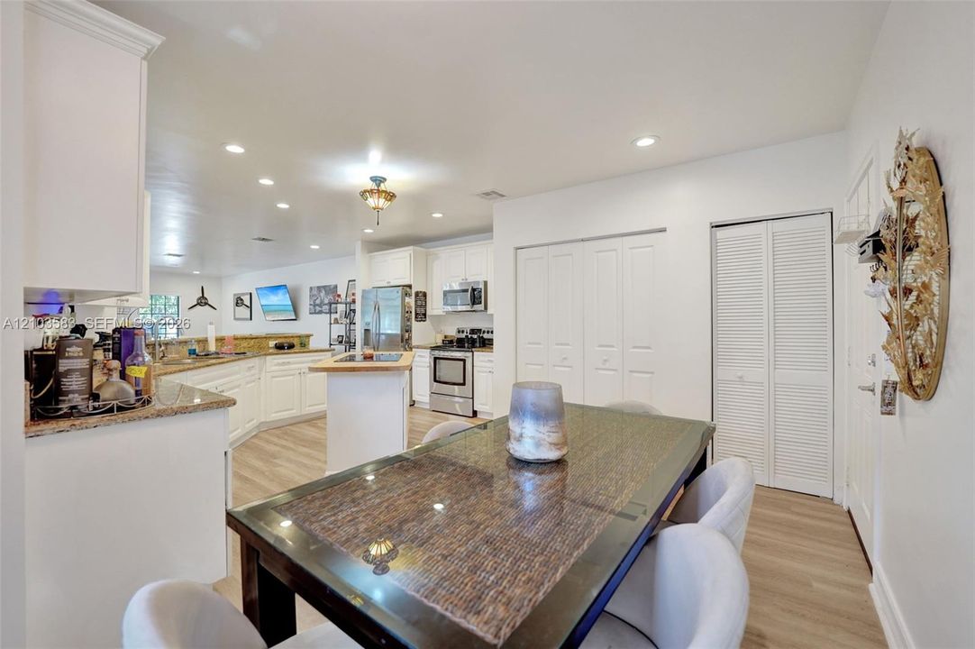 Kitchen featuring white cabinetry, stone countertops, stainless steel appliances, wood-finish flooring, and recessed lighting