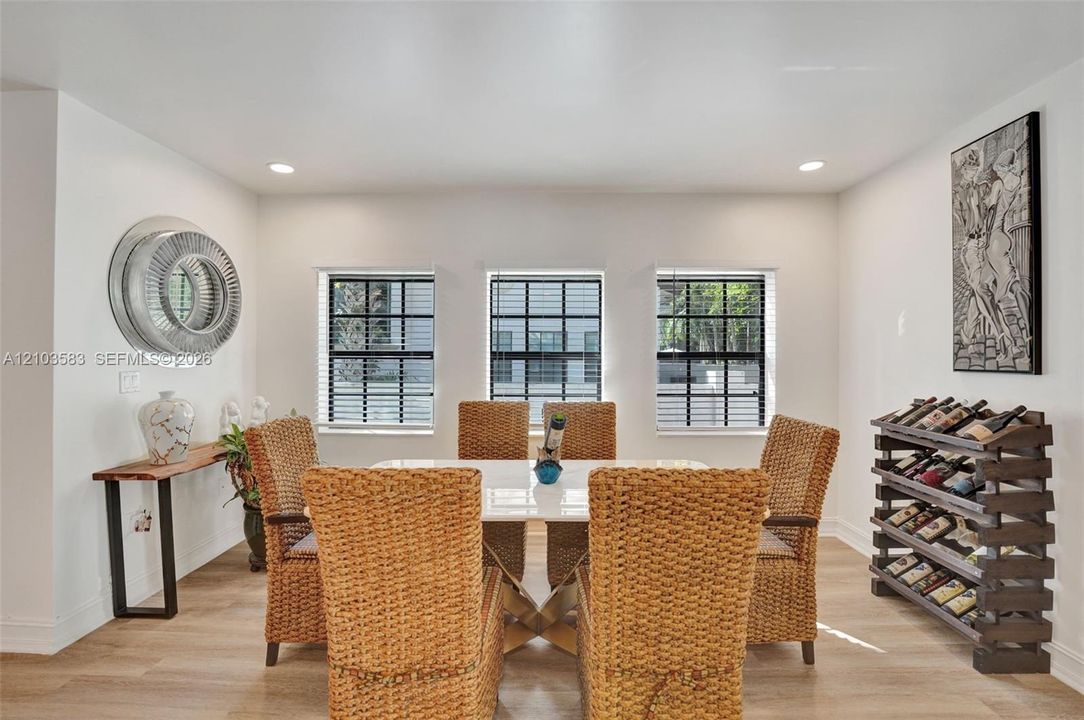 Dining area featuring wood-finish flooring, recessed lighting, and three grid-pane windows with integrated blinds