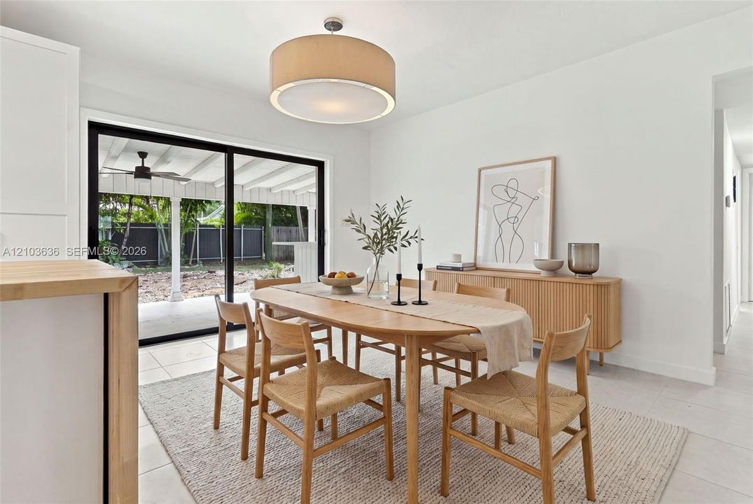 Large drum pendant lighting, light-toned flooring, and black-framed sliding glass doors opening to a covered patio