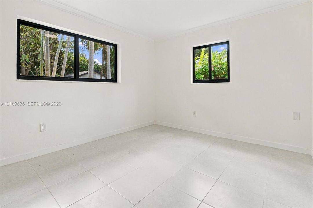 Neutral interior featuring large-format tile flooring, crisp white wall finishes, and black-framed windows