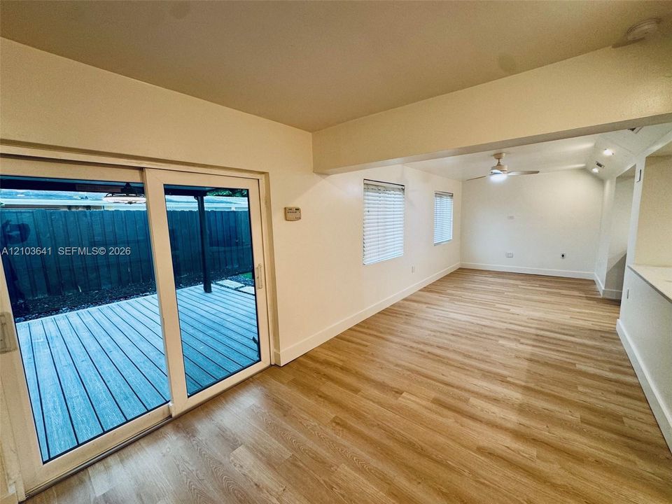 Interior space featuring wood-finish flooring, sliding glass doors, ceiling fan, and window blinds