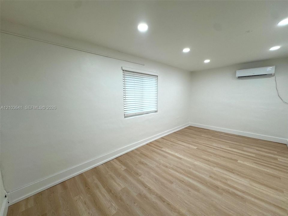 Interior space featuring recessed lighting, wood-finish flooring, a wall-mounted ductless air conditioning unit, and a window with blinds