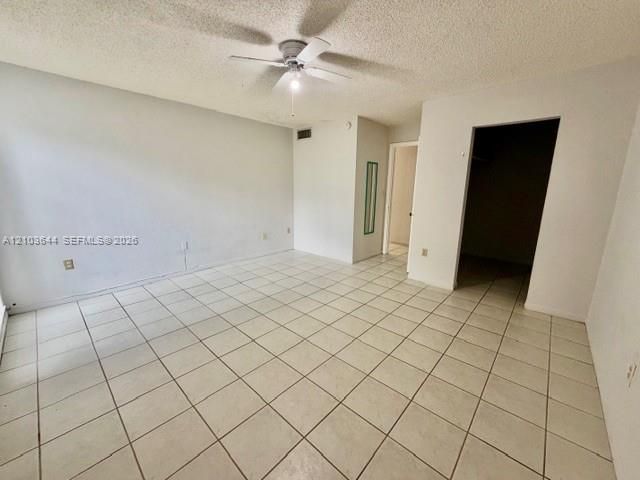 Spacious interior with tile flooring, white walls, and a ceiling fan with integrated lighting