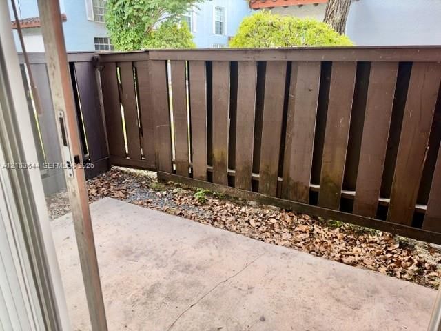 Private patio area with concrete flooring, framed by a wood-slat fence
