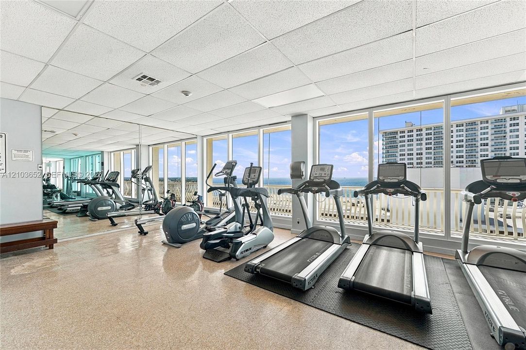 Fitness room featuring floor-to-ceiling windows, full-length wall mirrors, and resilient flooring