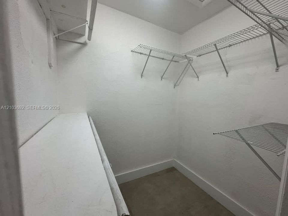 Walk-in storage space featuring tiered wire shelving units and a built-in solid-surface shelf