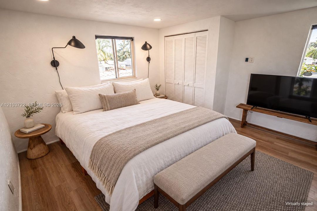 Wood-finish flooring, white walls, louvered-door closet, dual wall-mounted matte black swing-arm lamps, and recessed lighting
