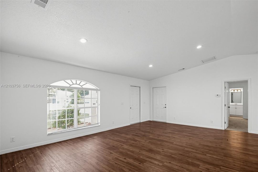 Vaulted ceilings, wood-finish flooring, recessed lighting, and a window featuring an arched transom