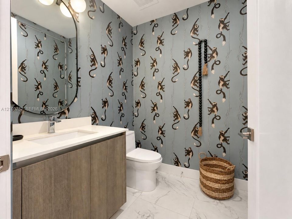 Wood-finish vanity with an integrated rectangular sink, wall-mounted oval mirror, and a three-light vanity fixture