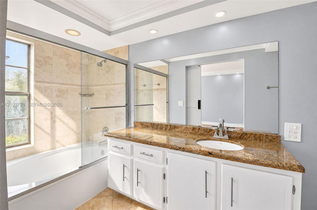 Bathroom featuring a large vanity with an undermount sink, a polished stone countertop, and white cabinetry with dark hardware