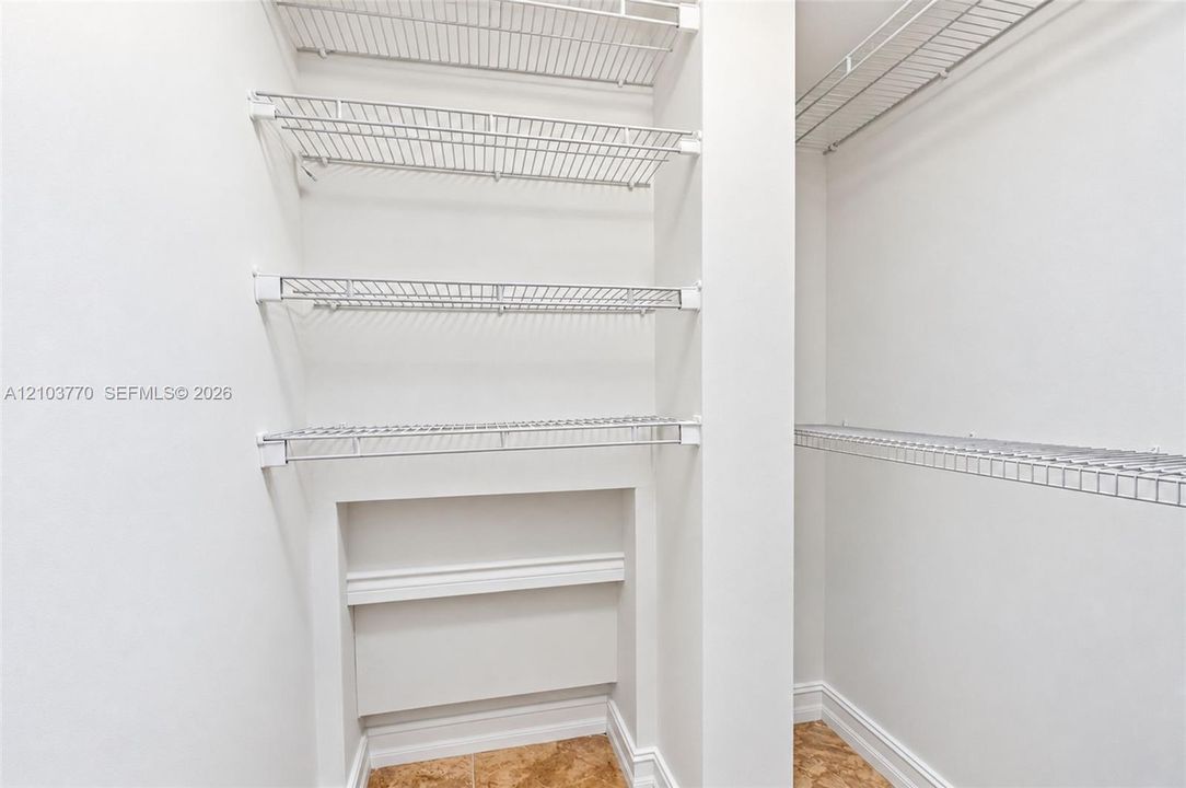 White wire shelving system, built-in lower shelving, white walls, and tile flooring