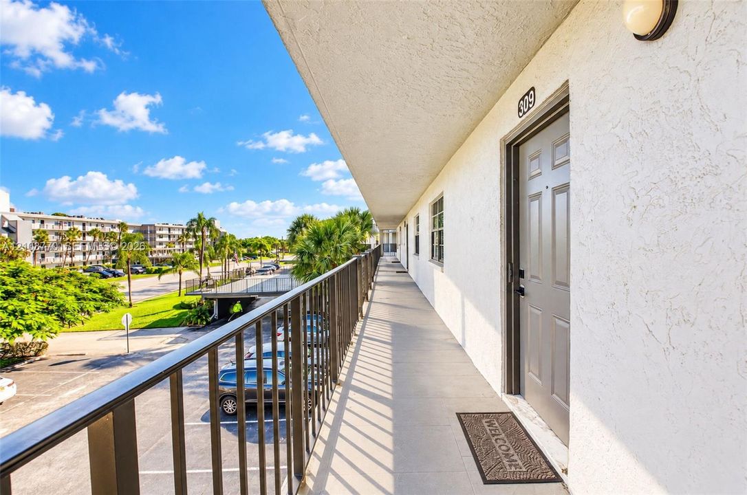 Upper-level walkway with a metal railing and stucco exterior