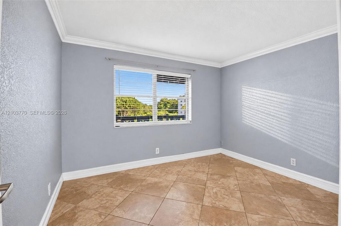 Window with horizontal blinds, crown molding, and tile flooring