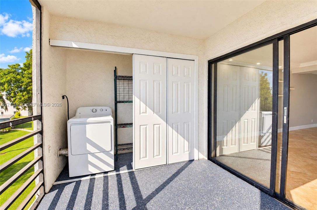 Balcony featuring a textured floor, sliding glass doors, and a laundry area with a dryer and shelving