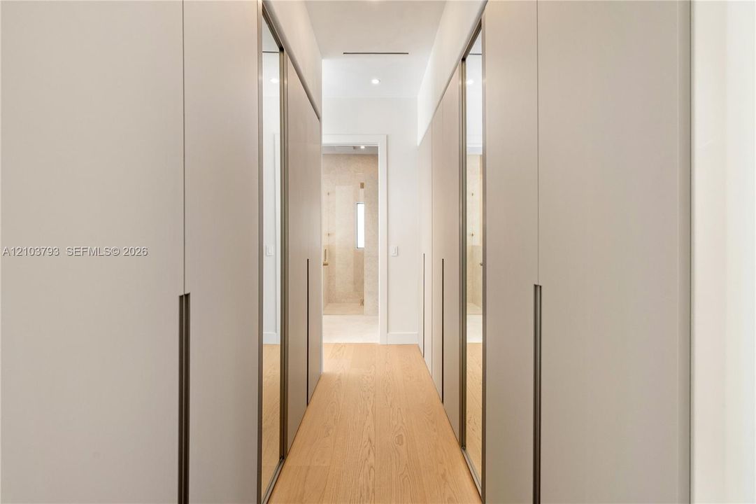 Custom floor-to-ceiling cabinetry with integrated mirror panels, long vertical hardware, and wood-finish flooring