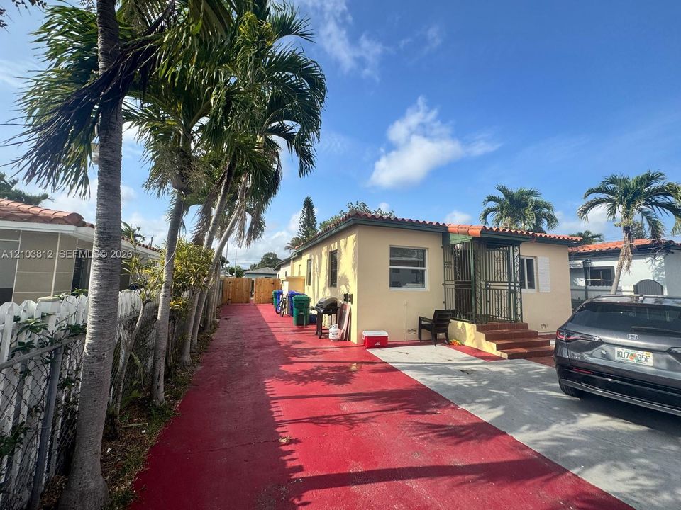 Single-story residence with a stucco exterior, terracotta tile roof, and a red-painted driveway