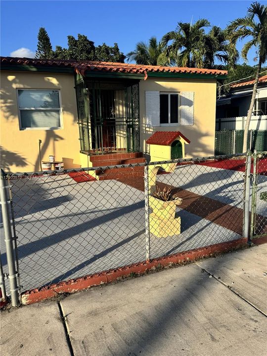 Stucco exterior with a tiled roof, covered entry, and security bars