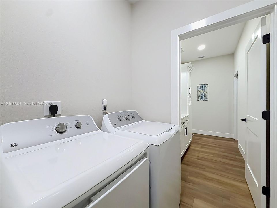 Laundry room featuring wood-finish flooring, white cabinetry, and recessed lighting